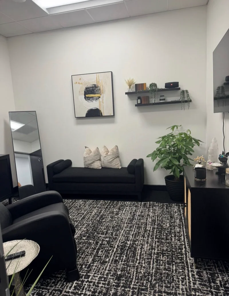 Inside The Polished Brow studio, with black seating, gold-accented artwork and plants.